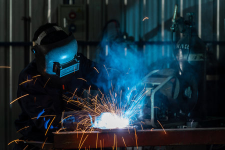 A craftsman or workers wearing industrial uniforms and welded iron mask at steel welding plants, Industrial safety first concept.の写真素材