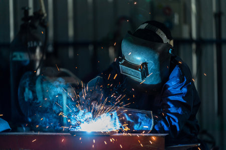 A workers wearing industrial uniforms and welded iron mask at steel welding plants, Industrial safety first concept.の写真素材
