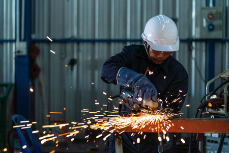 Asian heavy industry workers factory interior with industrial worker using angle grinder and cutting a steel.の写真素材