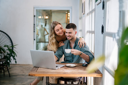 Smiling couple looking at laptop together at cozy home office. The concept of couples sharing one idea together.の写真素材