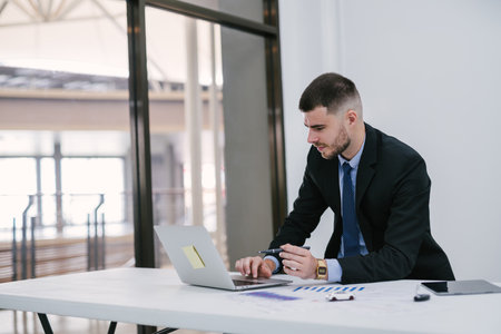 A caucasian male using laptop working at office. Car salesman planning to manage transportation finance costs. Dealership and online sales concept.の写真素材
