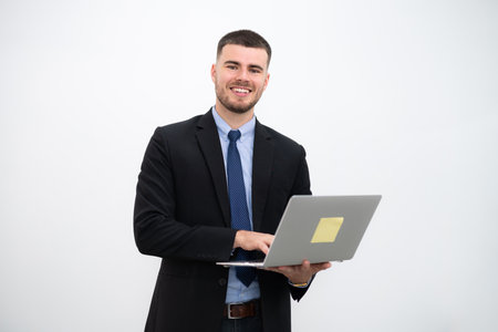 A businessman wearing a suit and Smiling young handsome looking at the camera with laptop on white background.の写真素材