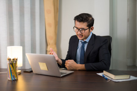 Asian handsome businessman sitting and discussing Discuss while meeting online with your laptop from home.の写真素材