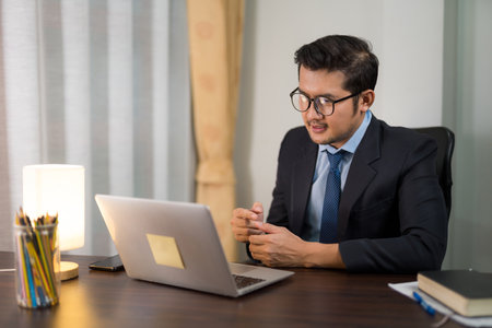 Asian businessman sitting and discussing online meeting with laptop in private office.の写真素材
