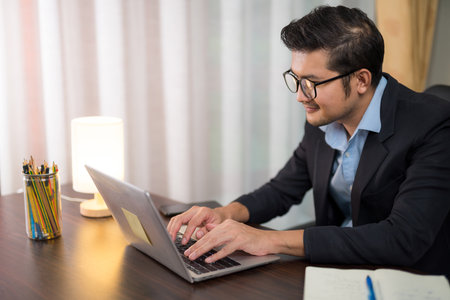 A businessman sitting at home working with laptop on desk.の写真素材
