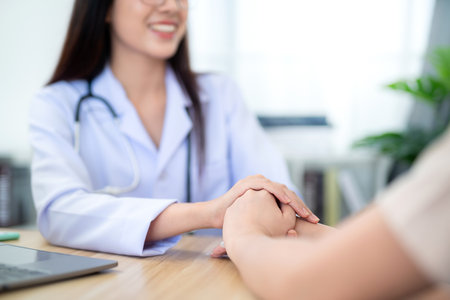 Close up hand of A female doctor holding female patient's hand to encourage treatment and health care at clinic. Health care concept.の写真素材