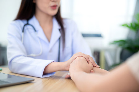 Hand of A female doctor holding female patient's hand to encourage medical treatment and health care in the hospital office. Health care concept.の写真素材