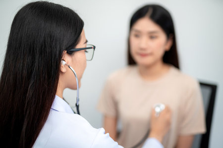 Asian female doctor using stethoscope to check patient's heartbeat at hospital. Medical and Health Care Concept. selective focus of stethoscope.の写真素材