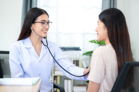 Asian female doctor using stethoscope to check patient's heartbeat at hospital. Medical and Health Care Concept.の写真素材
