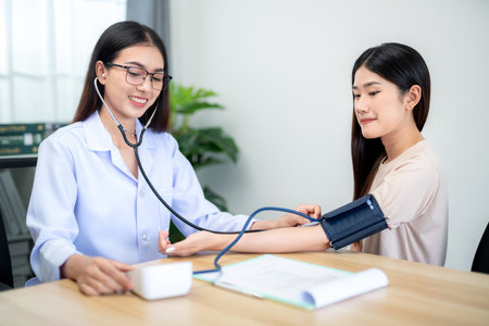A female doctor using digital sphygmomanometer and stethoscope to check patient's heartbeat at hospital. Medical and health concept.の写真素材