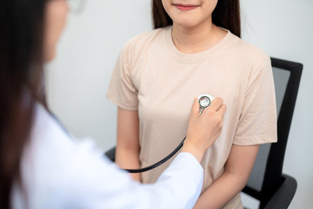 Close up of doctor using stethoscope putting beat heart diagnose with patient in examination room at a hospital. Medical and Health Care Concept.の写真素材