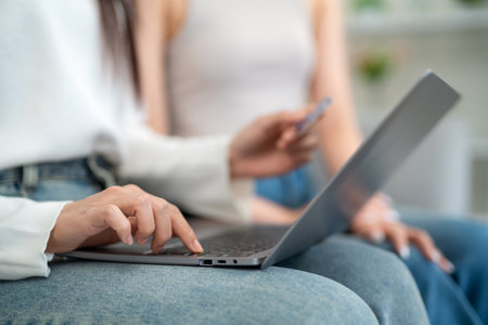 Close up hand of women shopping online shopping on laptop with credit card while sitting on sofa in living room. online shopping concept.の写真素材