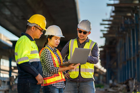 A team of professionals, civil engineers, architects are inspecting the expressway construction project site. With data on laptop at road construction site.の写真素材