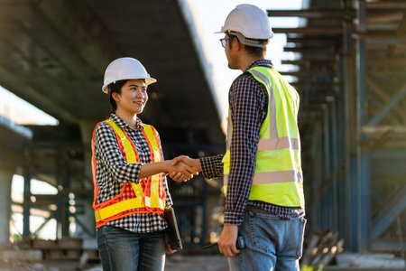 Asian women architect or construction workers in protective helmets and vests are shaking hands with engineer while working at the expressway construction site.の写真素材