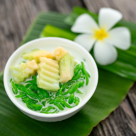 Appetizing lod chong placed on a green banana leaf decorated with white champa flowers on a wooden table.の写真素材