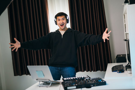 Asian dj man happy or DJ at a festival-like home event, mixer console set up with professional sound equipment and lighting.の写真素材