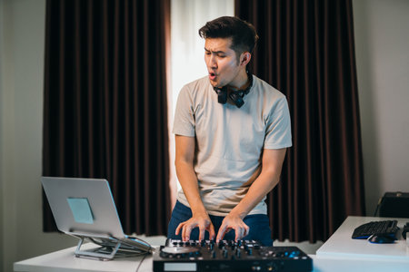 Asian DJ performing at a home, high-tech mixer console.