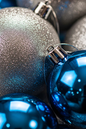 Close-up view of silver glitter and shiny blue Christmas baubles with festive lighting reflections, perfect for holiday decoration and seasonal celebration themesの素材