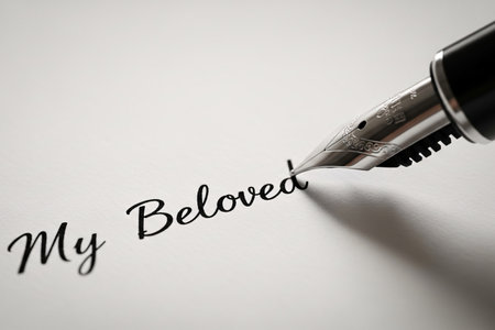 Detailed focus on the pen and glistening ink creating the romantic word "Beloved" symbolizing an important letter declaration.の素材