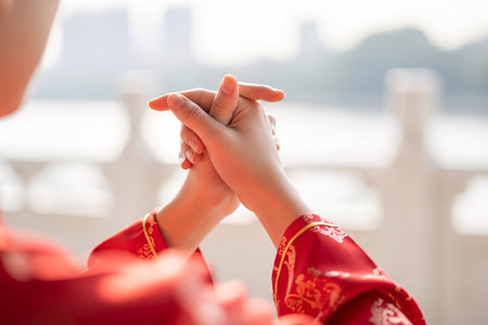 Hands making a traditional greeting with red Cheongsam sleeve convey wishes for prosperity and happiness.の素材