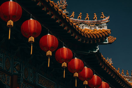 Vibrant red lanterns against a dramatic deep blue sky emphasize the intricate details of the temple roof.の素材