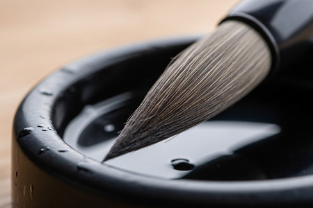 Close up of a calligraphy brush and dark inkwell showcasing the high detail texture of the tools used for the traditional cultural ritual.の素材