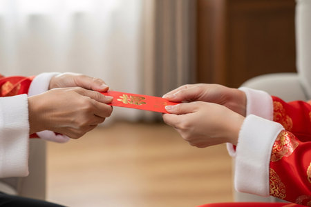 Chinese New Year greeting ritual with hands exchanging money packets a beautiful tradition symbolizing prosperity and family reunion.の素材