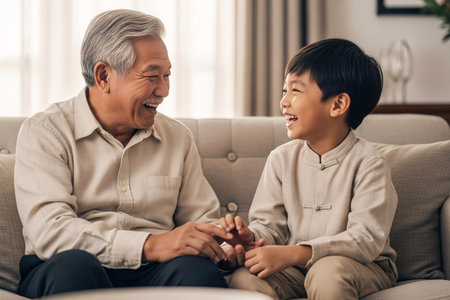 Grandfather and grandson sharing a genuine laugh during a heartwarming Lunar New Year family reunion celebration in an oriental setting.の素材