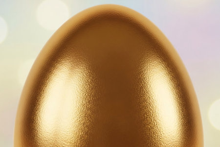 Close-up of a golden Easter egg with a reflective metallic texture and soft pastel bokeh background, symbolizing luxury and festive elegance.の素材