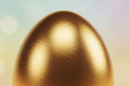 Close-up of a golden Easter egg with a reflective metallic texture and soft pastel bokeh background, symbolizing luxury and festive elegance.の素材