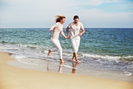 Young beautiful couple running around and spending good time on the beach on vacation.の写真素材