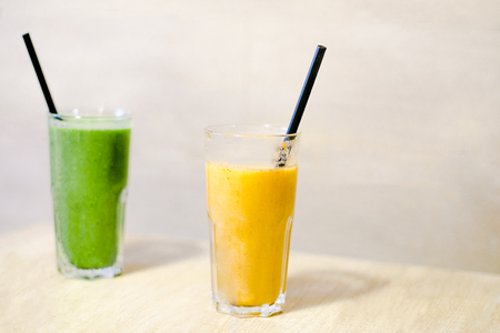 two smoothies ith straws are standing on the wooden tableの写真素材