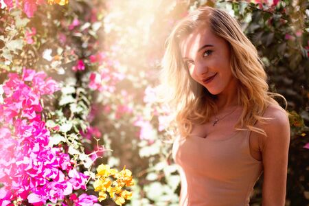 a young beautiful girl is standing near the pink  flowers and smilingの写真素材