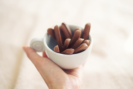 a female hand holding a cup of tasty chocolate biscuits for tea or coffee in the morning