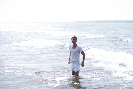 a model,a handsome sexy young man is standing in the sea and looking at you  ,sun is shiningの写真素材