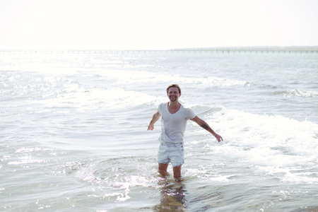 a model,a handsome positive young man is standing in the blue  sea and looking at you  ,sun is shiningの写真素材