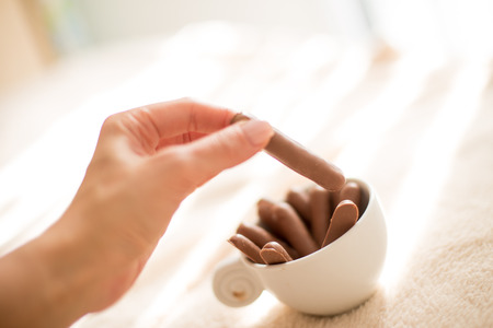 a female hand taking a tasty chocolate biscuit from the cup of  for tea or coffee in the morningの写真素材
