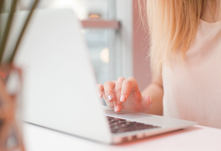elegant female hands are printing on a laptop in a cafe , business woman,