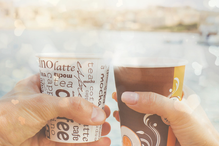 a young couple a man and woman ,holding cups of coffee in front of sea and blurred view ,love storyの写真素材