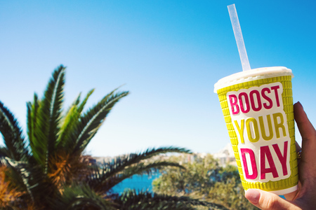 bright big plastic glass with words boost your day on the blue sky background and palm trees,a hot summer day,drink smoothieの写真素材