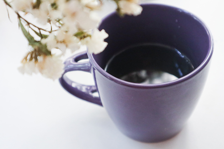 isolated purple cup of coffee with a spring bouquet of white flowers in the morning on a white backgroundの写真素材