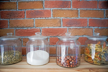 Walnuts, pasta,grains and salt in glas jars in modern loft design kitchen in front of bricked wall, cooking healthyeating conceptの写真素材