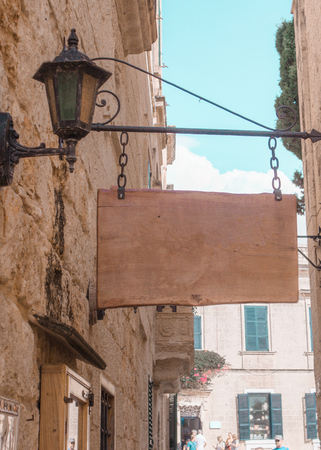 Wooden hanging rectangle sign on the background on the wall of vintage homes. old city, light colors,blue skyの写真素材