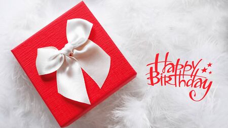 close up of a beautiful white and red gift box as a birthday present , in white feathersの写真素材