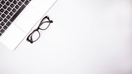 gray laptop with  black  glasses on white background table, working place at home or in the officeの写真素材