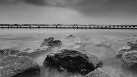 Black and white photo of the wooden bridge along the beachの写真素材