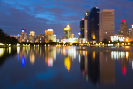 Out of fucus building city night lights blurred bokeh background with water reflectionの写真素材