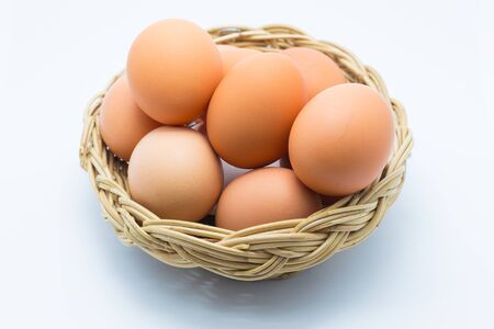 Chicken eggs in a basket on whiteの写真素材