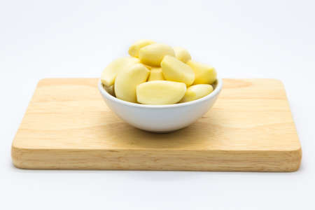 Cup of fresh garlic on wooden board, white backgroundの写真素材