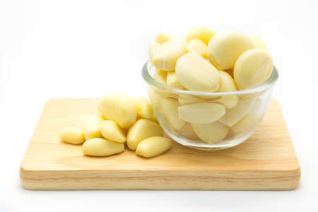 Glass cup of garlic on wooden board, on white backgroundの写真素材